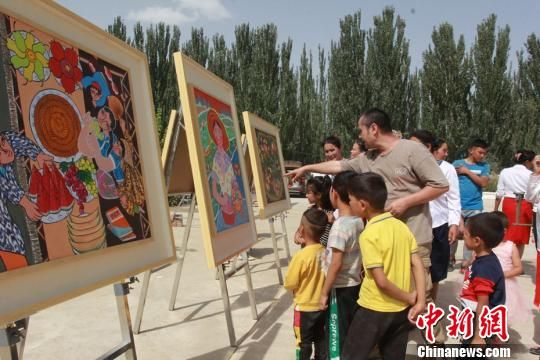 新疆维吾尔自治区文化馆25日为新疆墨玉县喀瓦克乡农民举办新时代下图片展活动。　陶拴科　摄