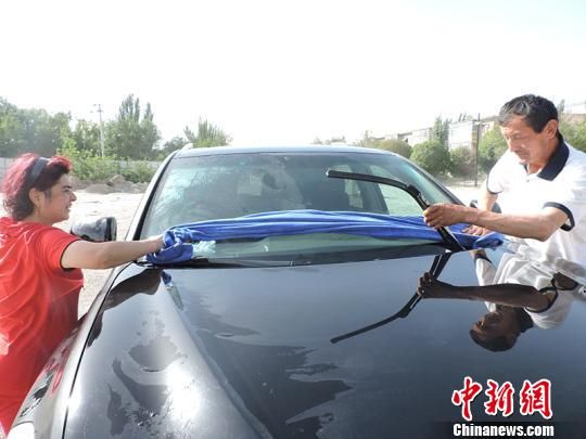 米日古丽·吾布力和丈夫为车主洗车。　胡浩浩　摄