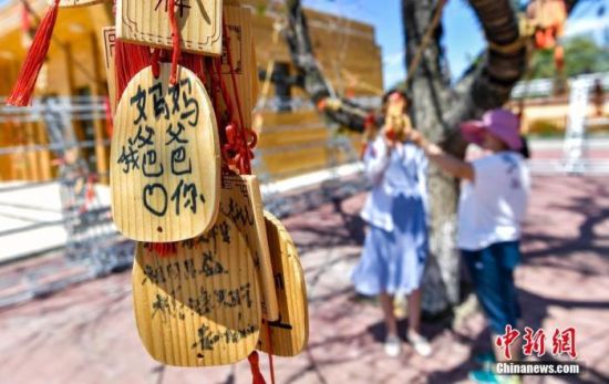 6月2日，新疆阿勒泰地区福海县阔克阿尕什乡阿克乌提克勒村，该村文化广场的树上挂满游客留下的许愿牌。中新社记者 刘新 摄